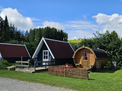 Schlafhütte und Fässer am Campingplatz Gelände